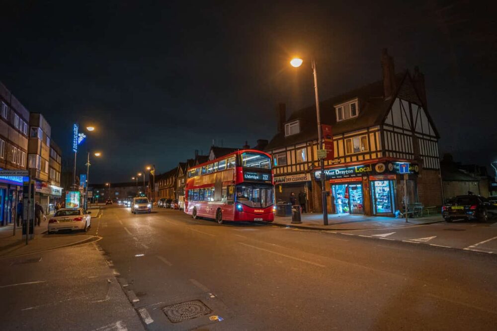 street view of a bus and shops at night, near a drug and alcohol rehab in hillingdon